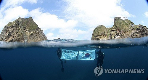 독도 일대를 조사 중인 한국해양과학기술원 울릉도독도해양연구기지 직원들이 광복절을 앞둔 14일 독도의 하늘과 바다를 배경으로 태극기를 펼쳐 보이고 있다.  [울릉도독도해양연구기지 제공]